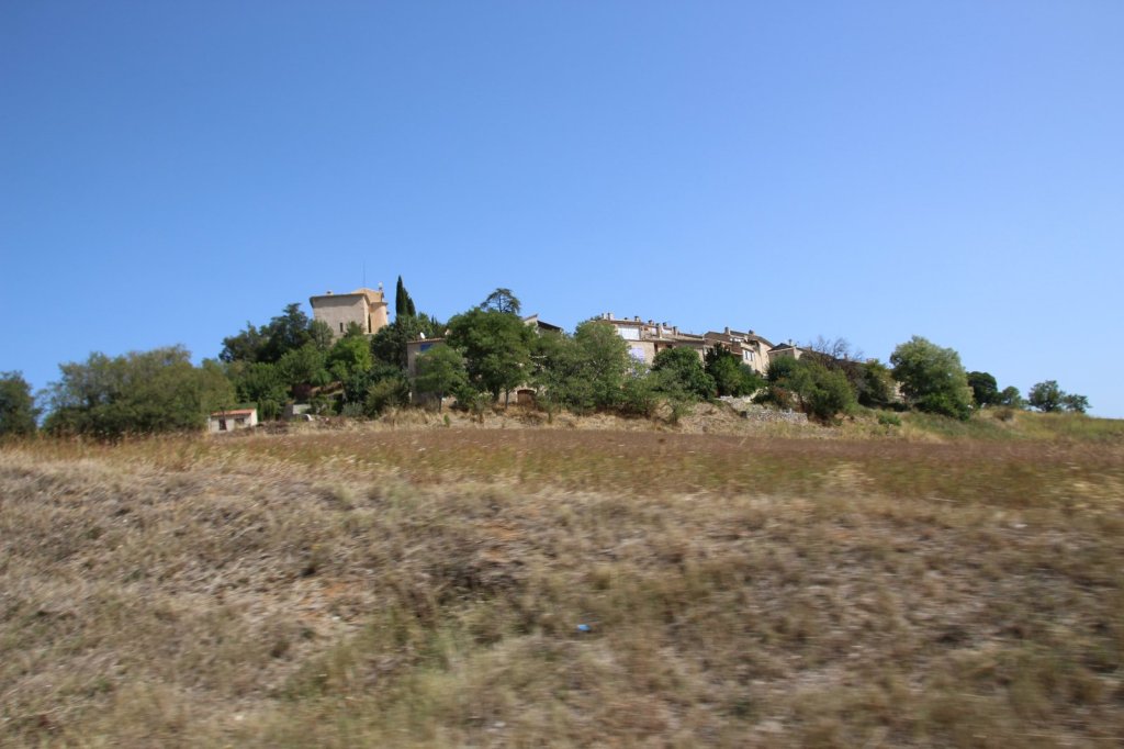 Kleines Dorf auf einem Hügel hinter trockenem Gras in der Provence