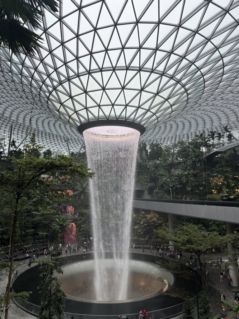 Riesiger Indoor-Wasserfall im Jewel Changi, umgeben von Dschungelbepflanzung und einer Glaskuppel