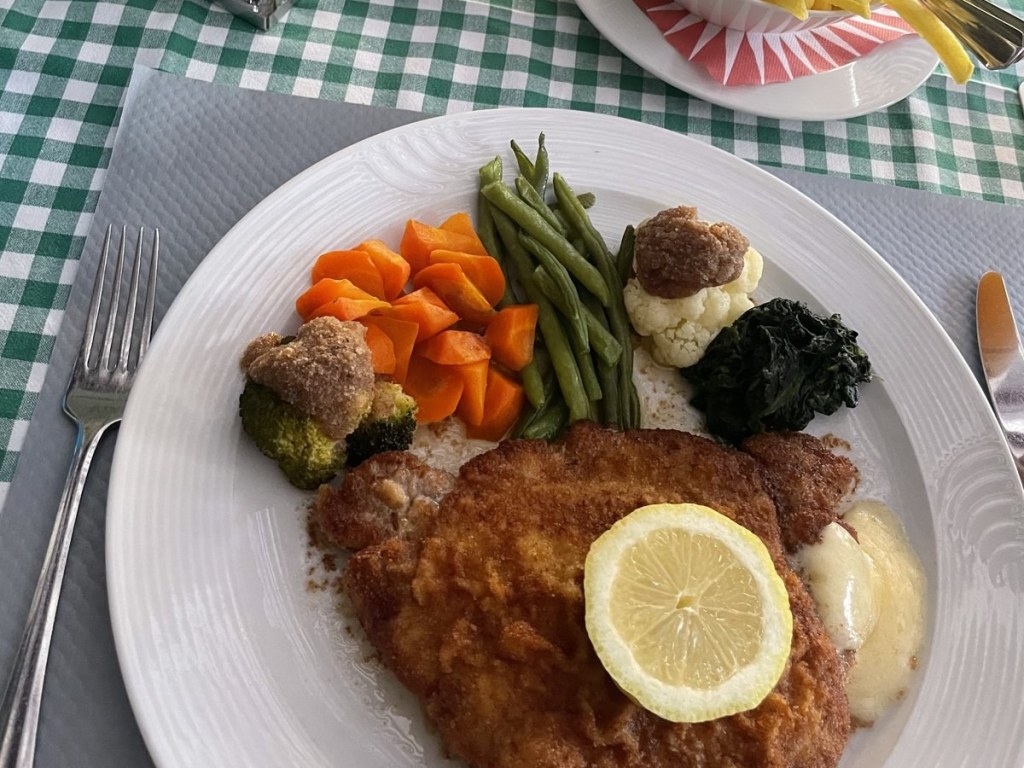 Paniertes Schnitzel mit Gemüse auf einem weißen Teller