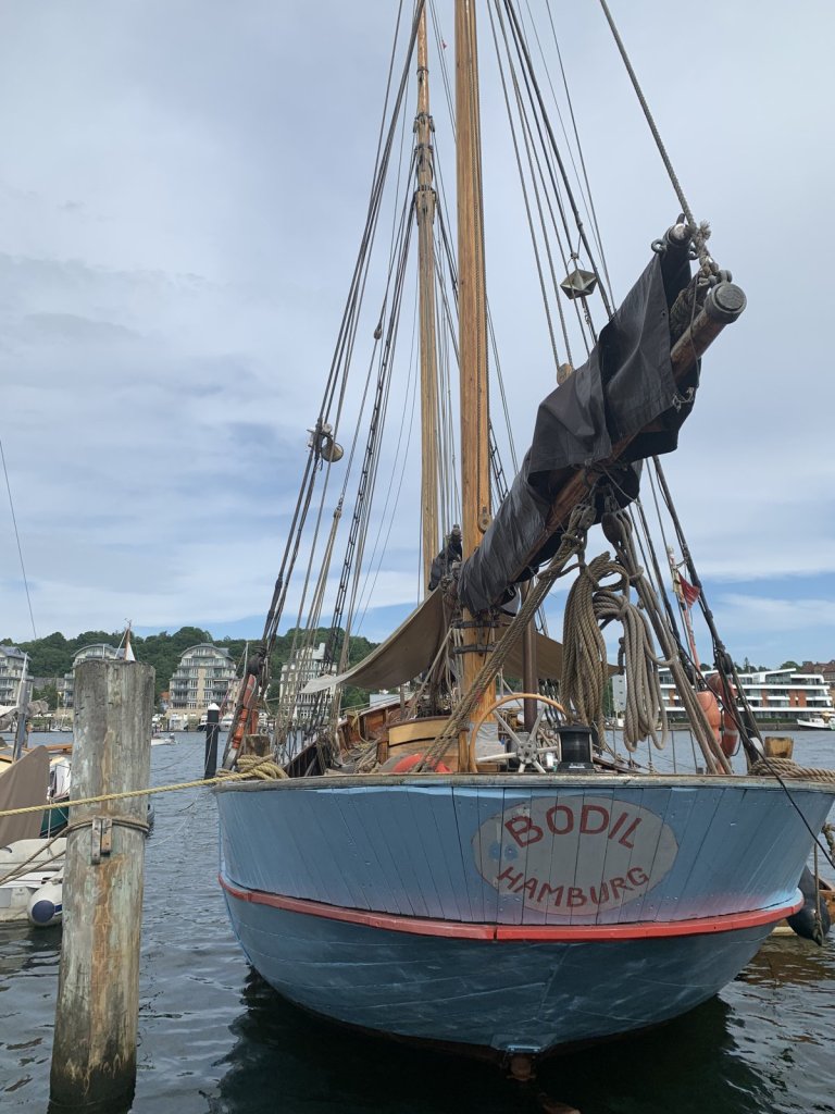 Blauer Traditionssegler mit Mast am Hafen von Flensburg