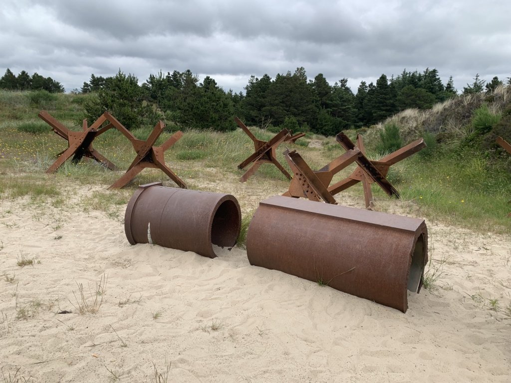 Rostige Panzersperren und Rohre im Sand an der dänischen Nordsee