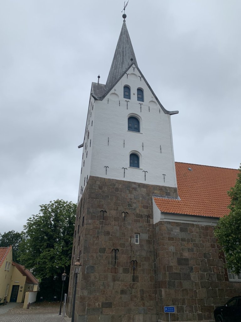 Weiß-roter Kirchturm mit Backsteinsockel in Varde