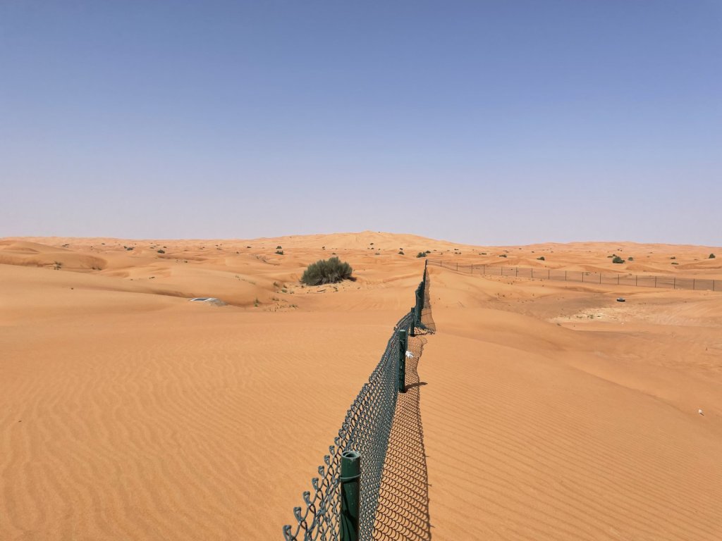 Orange Sanddünen mit einem Zaun bis zum Horizont