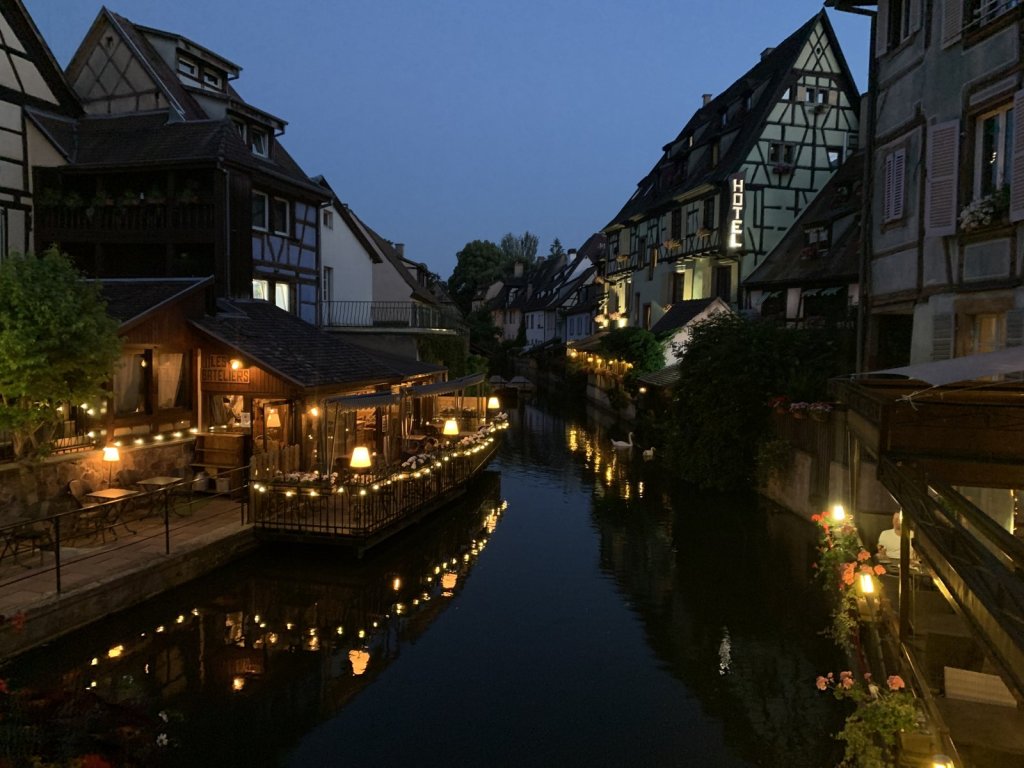 Beleuchtete Fachwerkhäuser und Restaurants an einem Kanal in Colmar bei Nacht