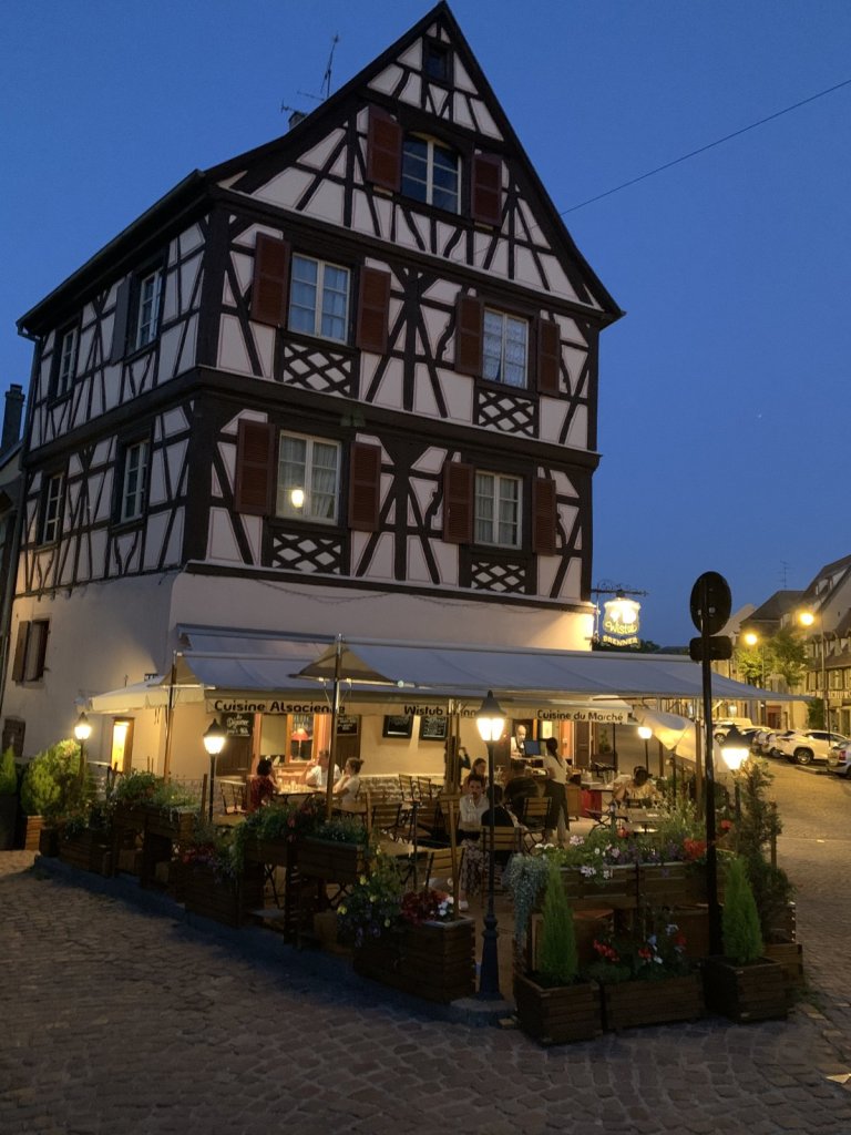 Beleuchtetes Fachwerkhaus mit Gartenwirtschaft in Colmar in der Dämmerung