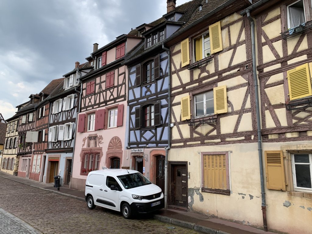 Gasse mit bunten Fachwerkhäusern und gelben Fensterläden in Colmar
