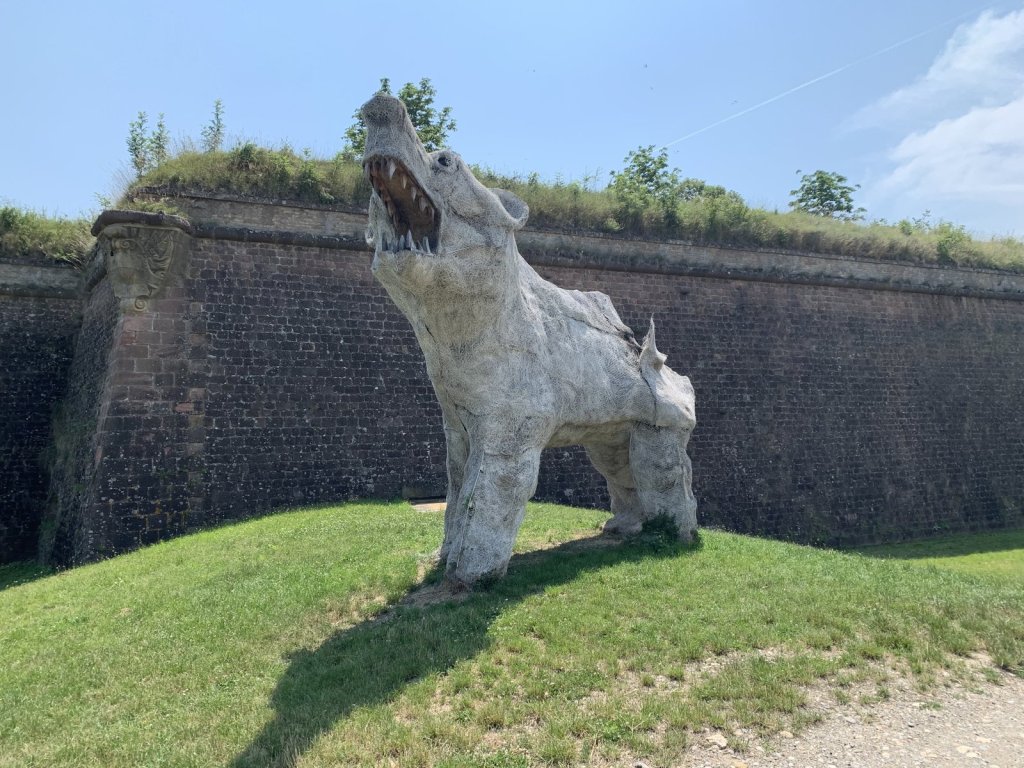 Große weiße Wolfsskulptur vor den Backsteinmauern der Festung Neuf-Brisach
