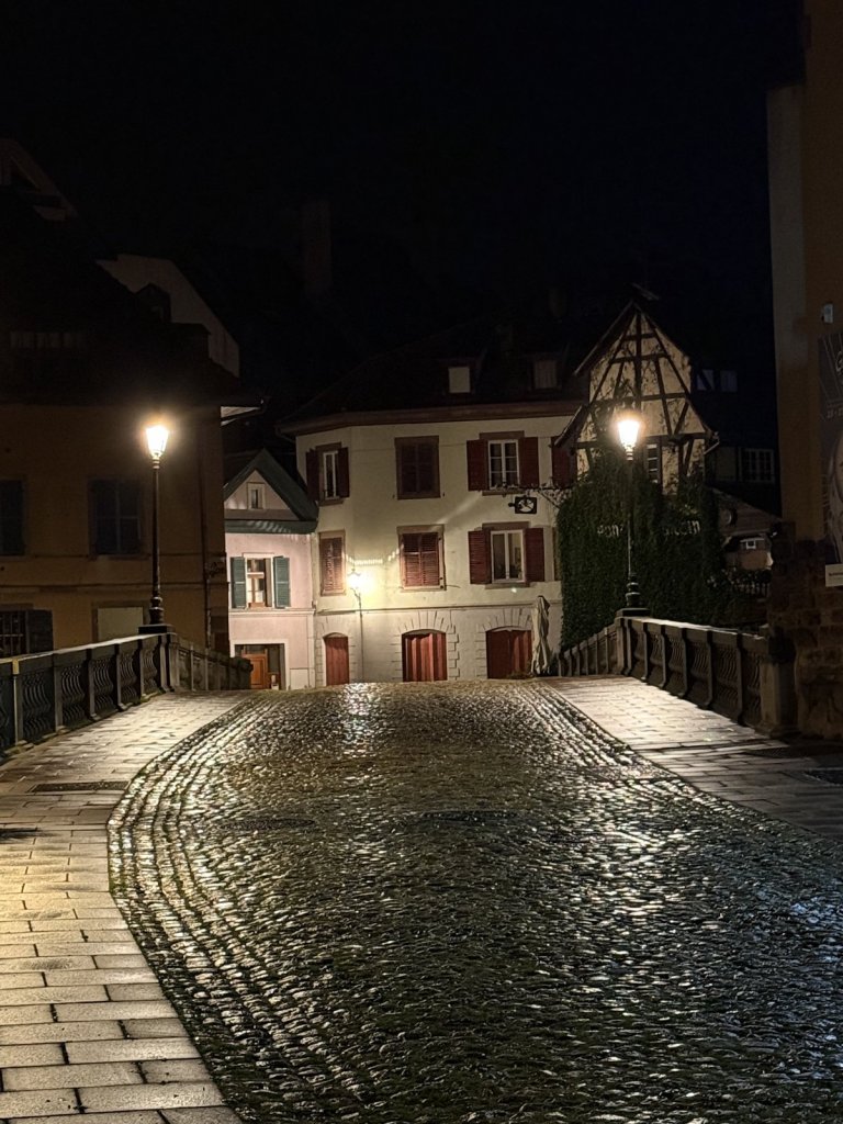 Beleuchtete Häuser an einer Steinbrücke über einen Kanal in Straßburg bei Nacht