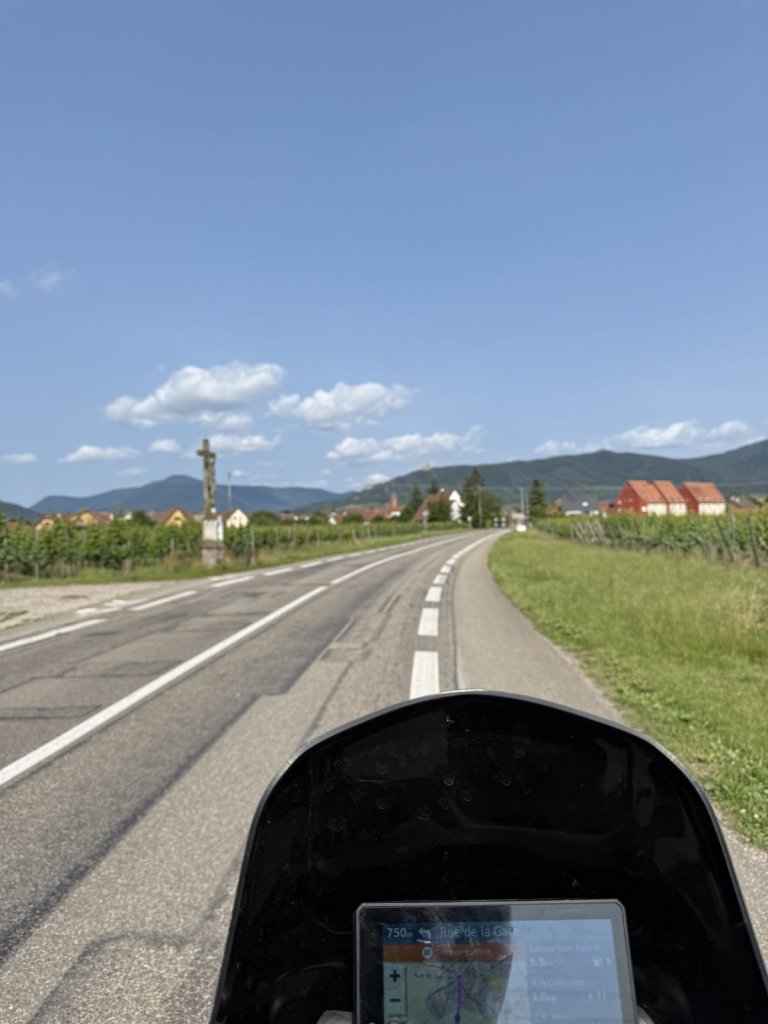 Straße durch die Weinberge im Elsass, im Vordergrund die Scheibe des Motorrads