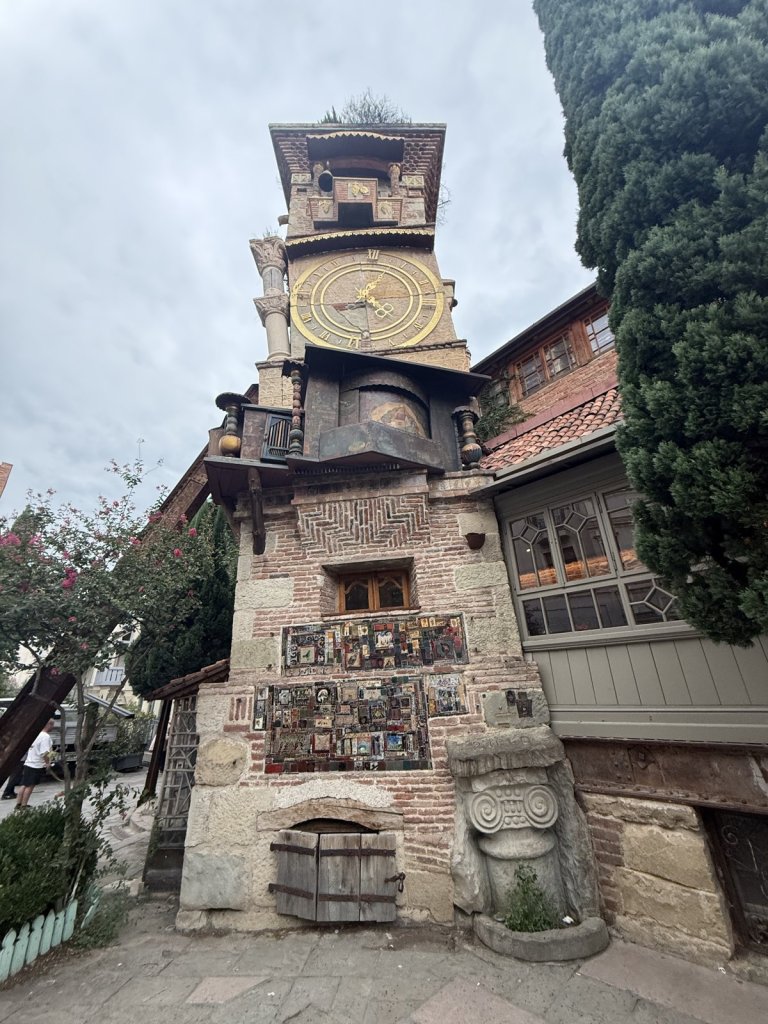 Schiefer Uhrenturm aus Backstein und Holz neben einem Theater in Tiflis