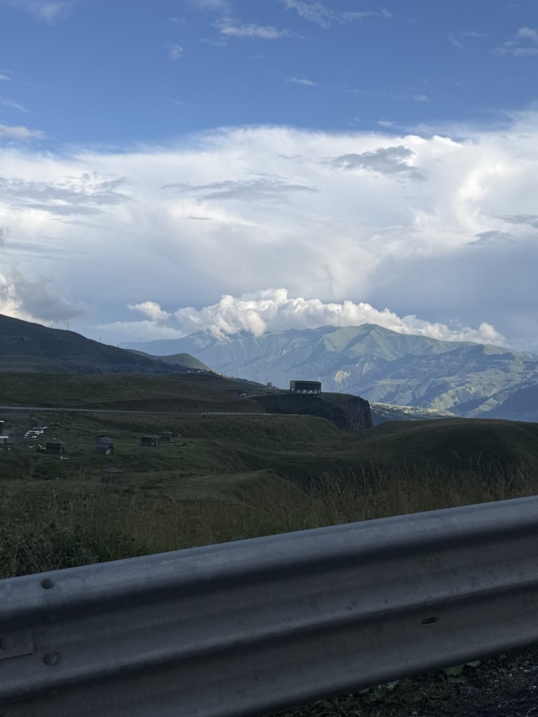 Berge und Wolken im Kaukasus hinter einer Leitplanke