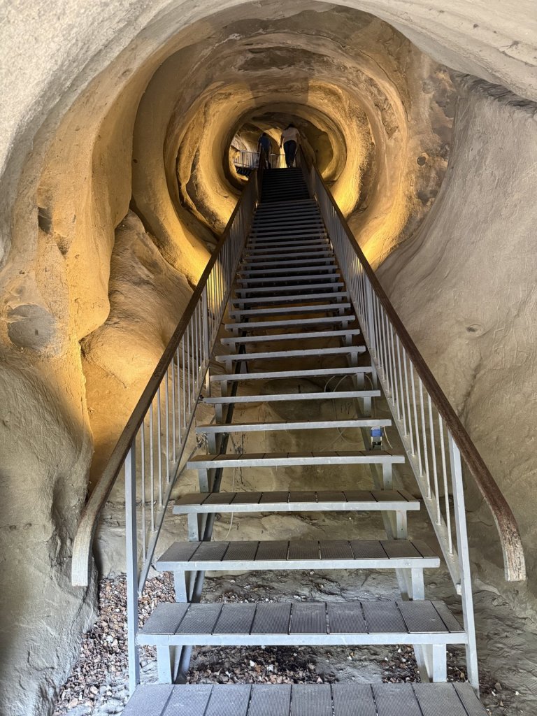 Beleuchteter Felstunnel mit Metalltreppe in der Höhlenstadt Uplisziche
