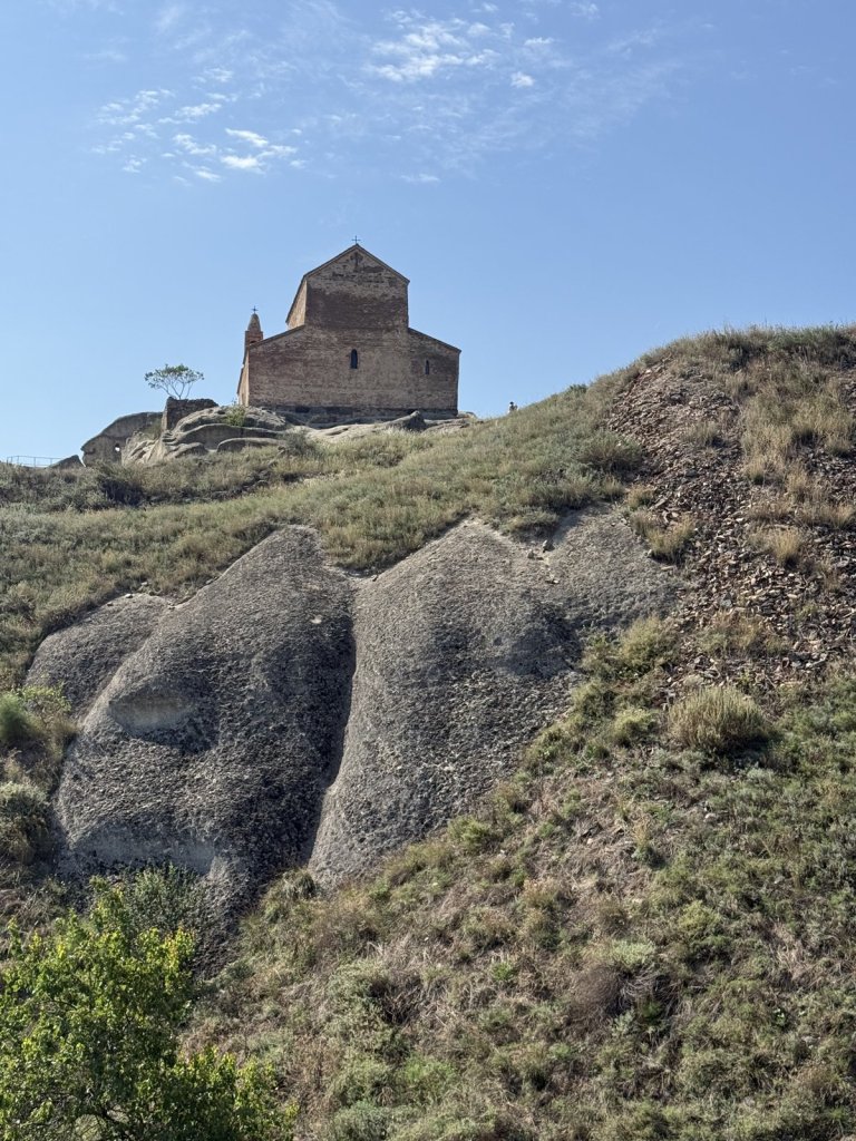 Kleine Steinkirche auf einem Hügel mit Felsen im Vordergrund