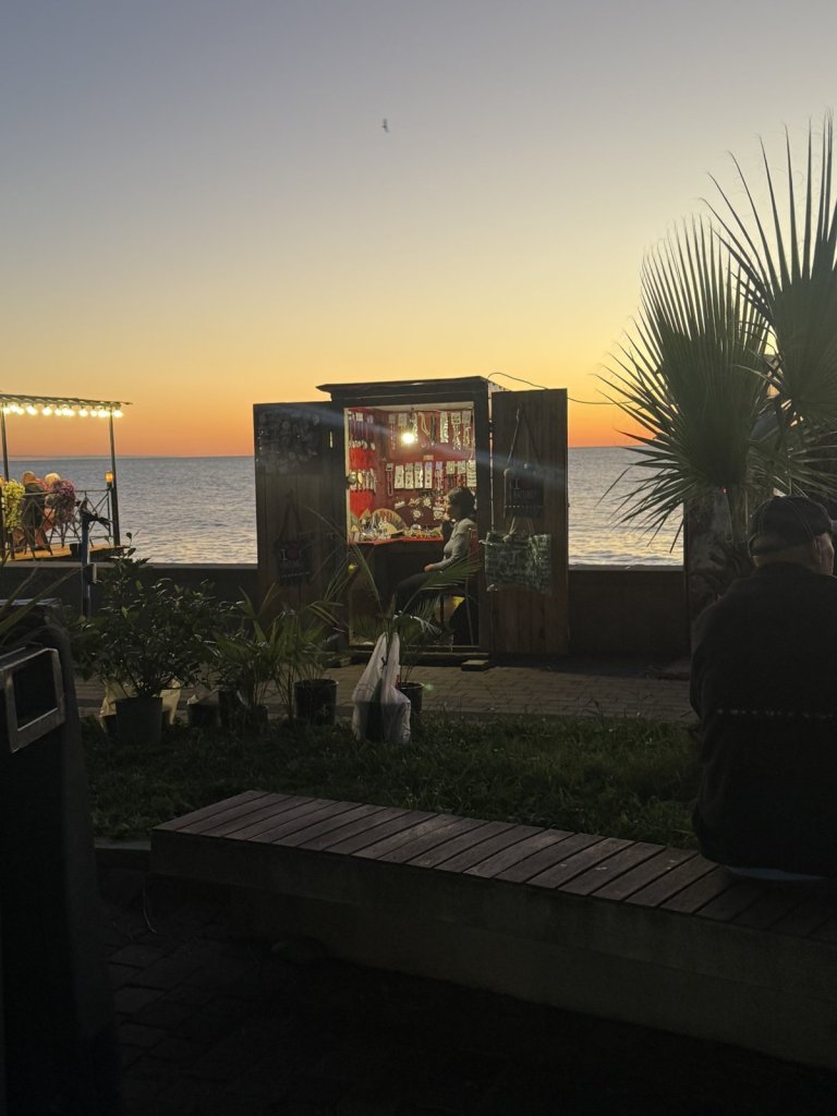 Beleuchteter Kiosk an der Strandpromenade vor dem Sonnenuntergang am Meer