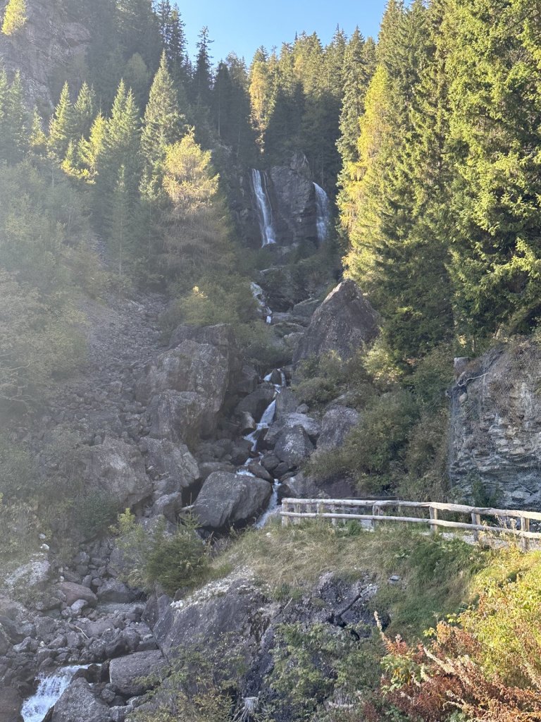 Wasserfall zwischen Felsen und Lärchen im Herbst