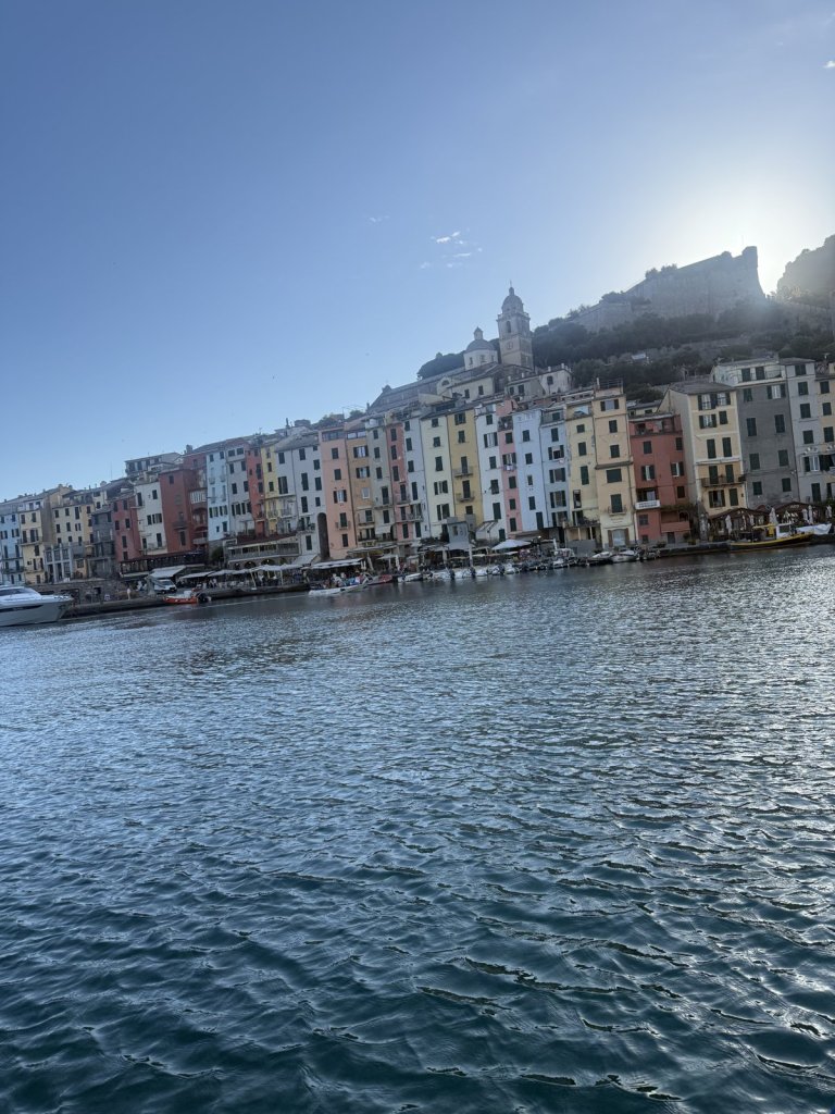 Bunte Häuser von Portovenere am Ufer, darüber die Burg im Gegenlicht
