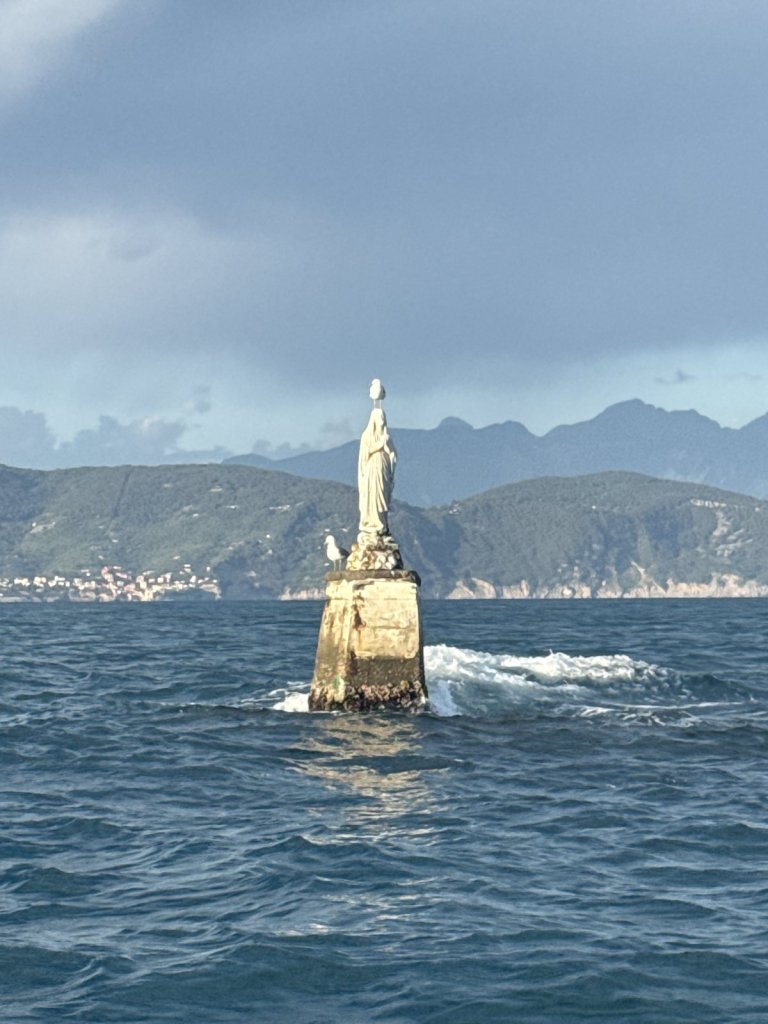 Weiße Madonnenstatue auf einem Sockel im Meer vor der Küste