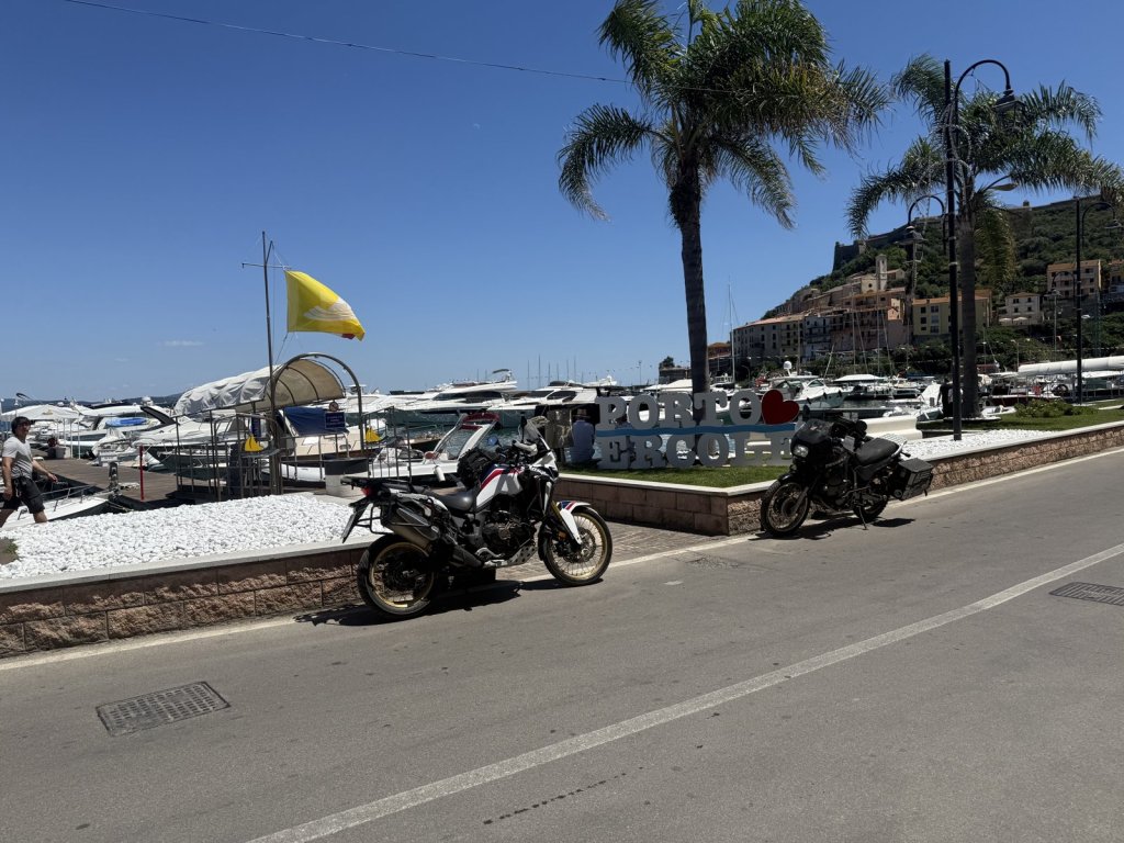 Zwei Motorräder an einer Hafenpromenade mit Palmen am Monte Argentario
