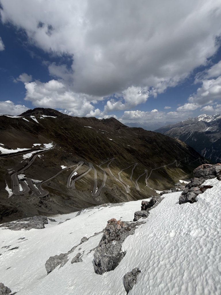 Schneefeld und Kehren der Passstraße unter Wolken