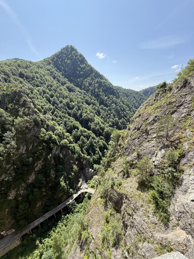 Steg an einer steilen bewaldeten Felswand unterhalb des Vidraru-Staudamms