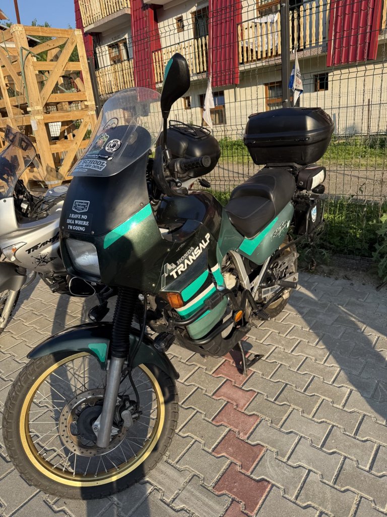 Grün-silberne Honda Transalp mit Koffer auf Pflastersteinen