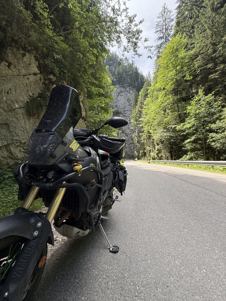 Schwarzes Reisemotorrad an der Straße in einer engen bewaldeten Schlucht