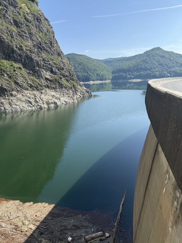 Blauer Stausee zwischen Bergen neben der Mauer des Vidraru-Damms