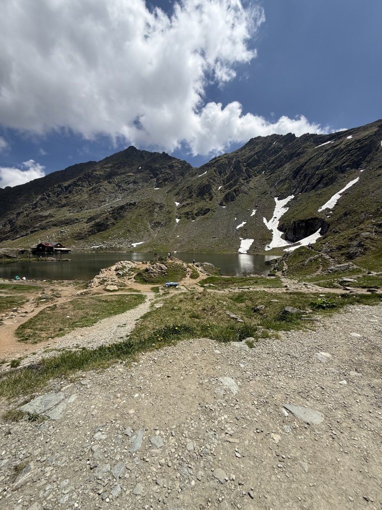 Hochgebirgssee mit Schneeresten und Berghütte