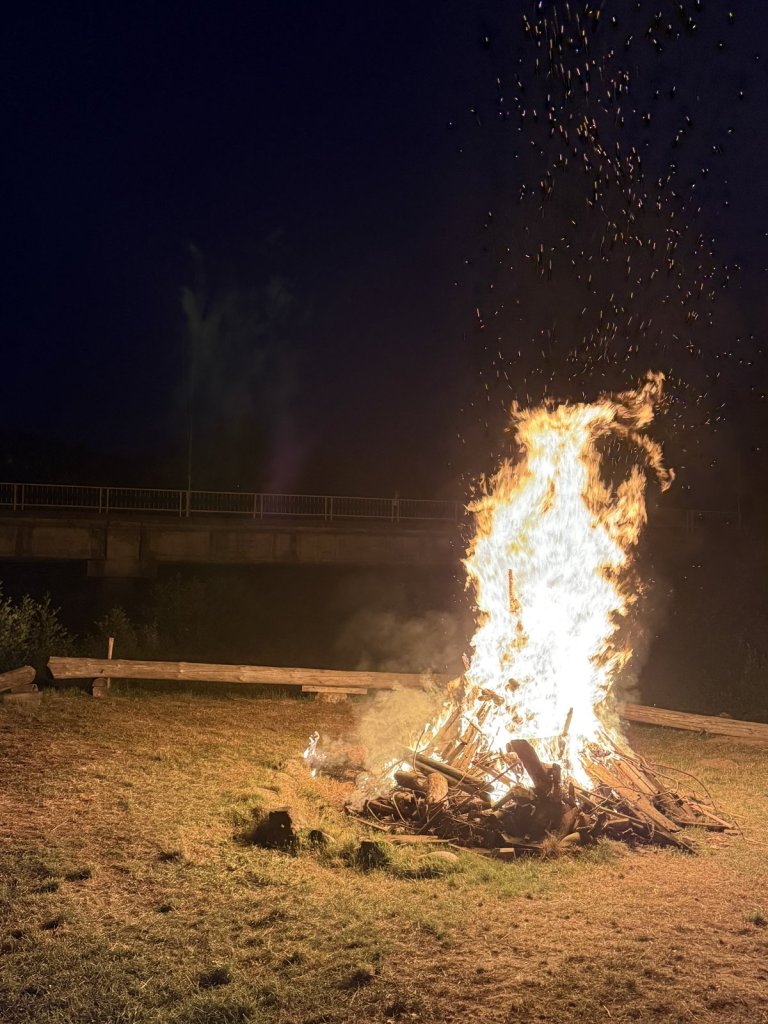 Hohes Lagerfeuer auf einer Wiese bei Nacht