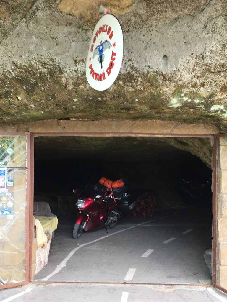 Motorrad im Eingang einer Felsenhöhle mit Logo des Motoklubs
