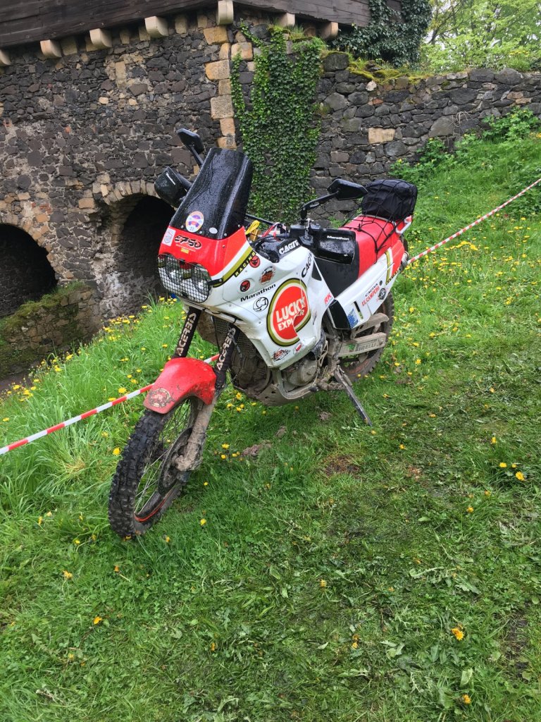 Rot-weiße Rallye-Enduro mit Absperrband an einem Grashang vor der Burgmauer