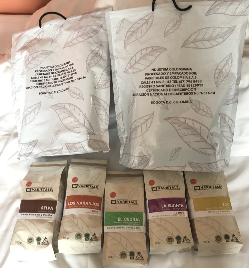 Mehrere Tüten kolumbianischer Spezialitätenkaffee verschiedener Sorten auf einem Bett