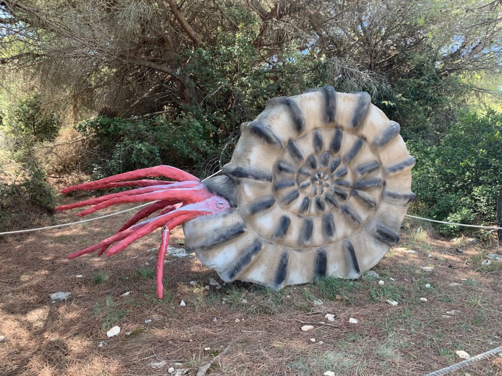 Große Skulptur eines Ammoniten mit rosa Fangarmen im Wald bei Pula