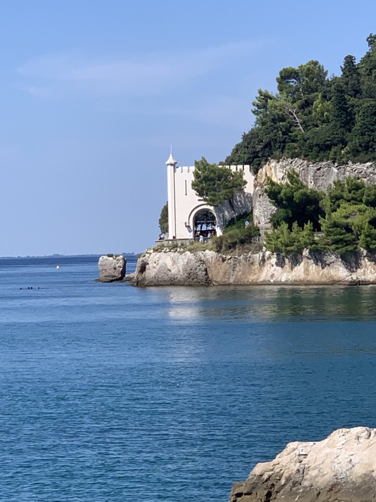 Weißes Schloss Miramare auf einer Felsspitze am Meer