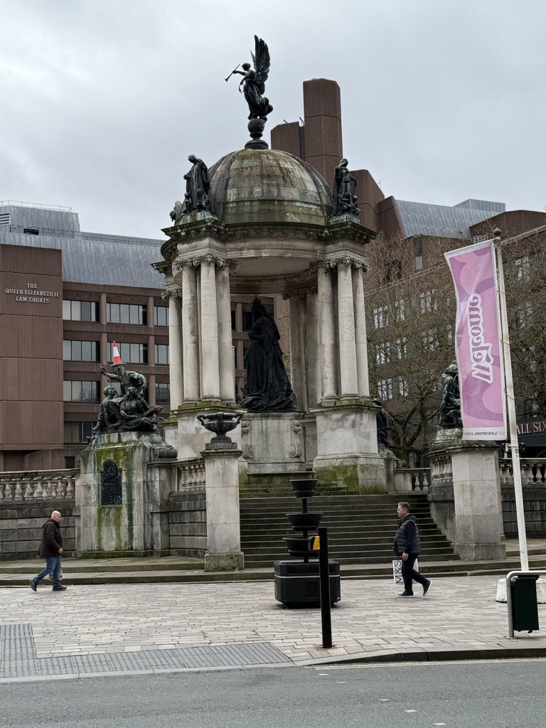 Denkmal mit Figuren auf einem Sockel vor modernen Gebäuden in Liverpool