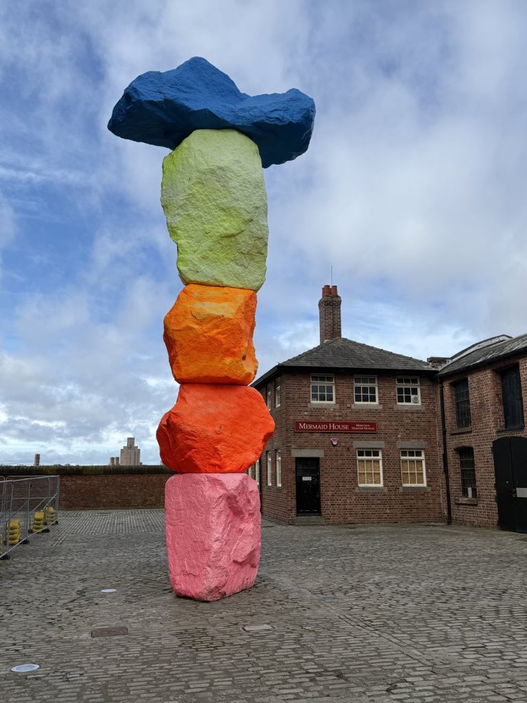Bunte gestapelte Steinskulptur vor Backsteinbauten am Albert Dock