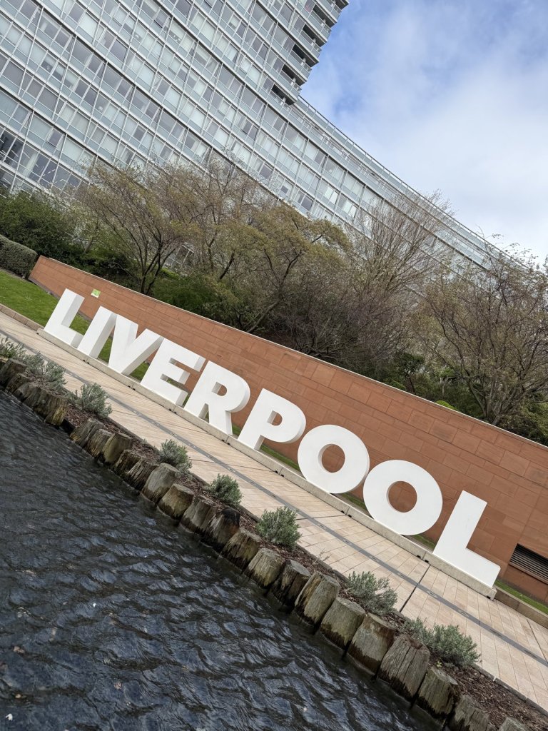 Großer Schriftzug Liverpool aus Buchstaben am Wasser vor Hochhäusern