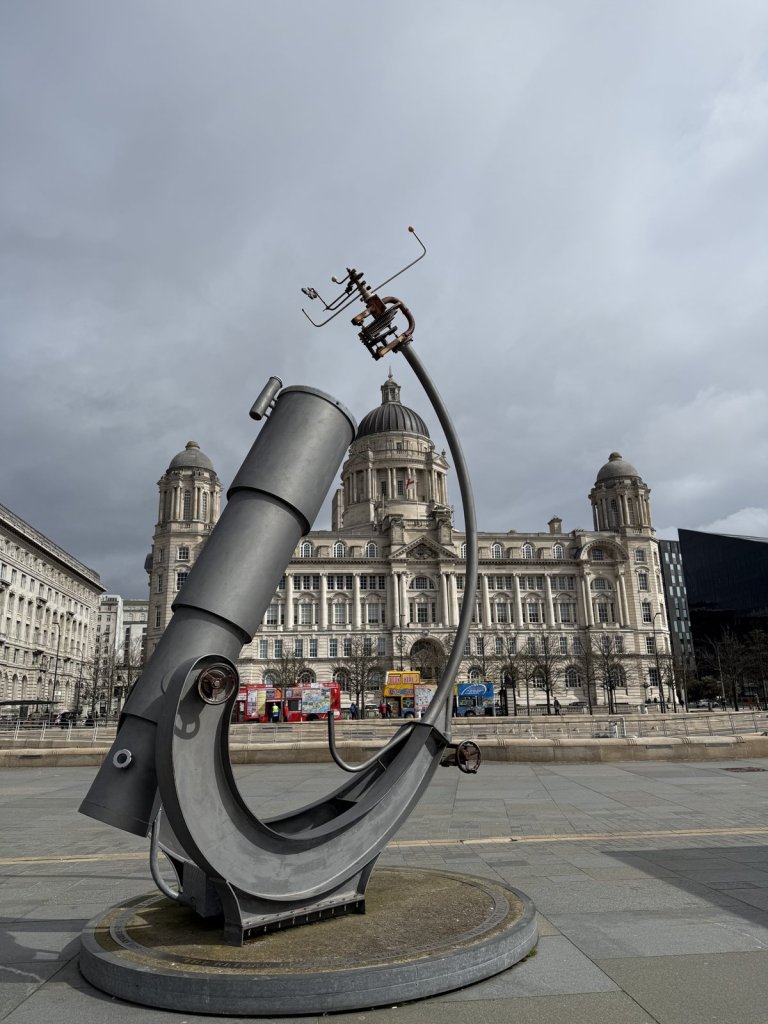 Skulptur mit einem Fernrohr vor Gebäuden am Hafen in Liverpool