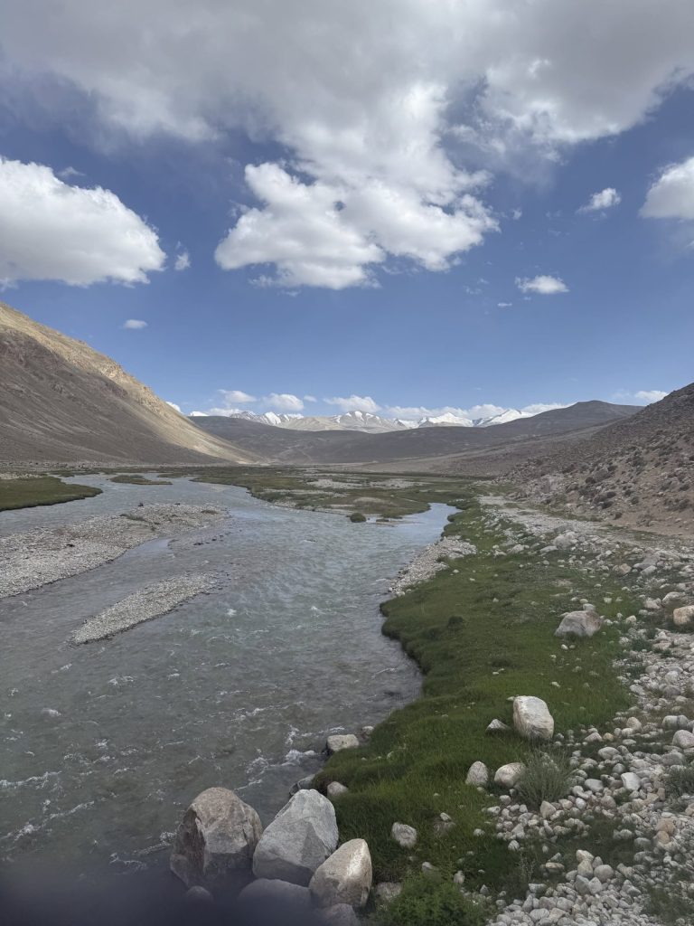 Fluss mit grünen Ufern in einem kargen Hochtal im Pamir