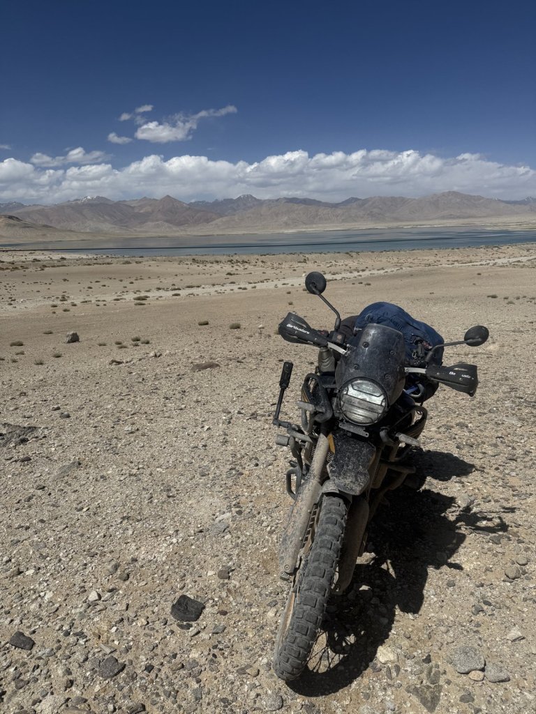 Motorrad auf steiniger Hochebene, dahinter ein See und Wolken