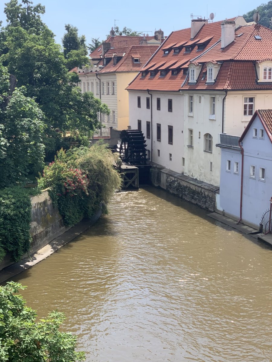 Kanal Čertovka mit Mühlrad zwischen Häusern auf der Kleinseite in Prag