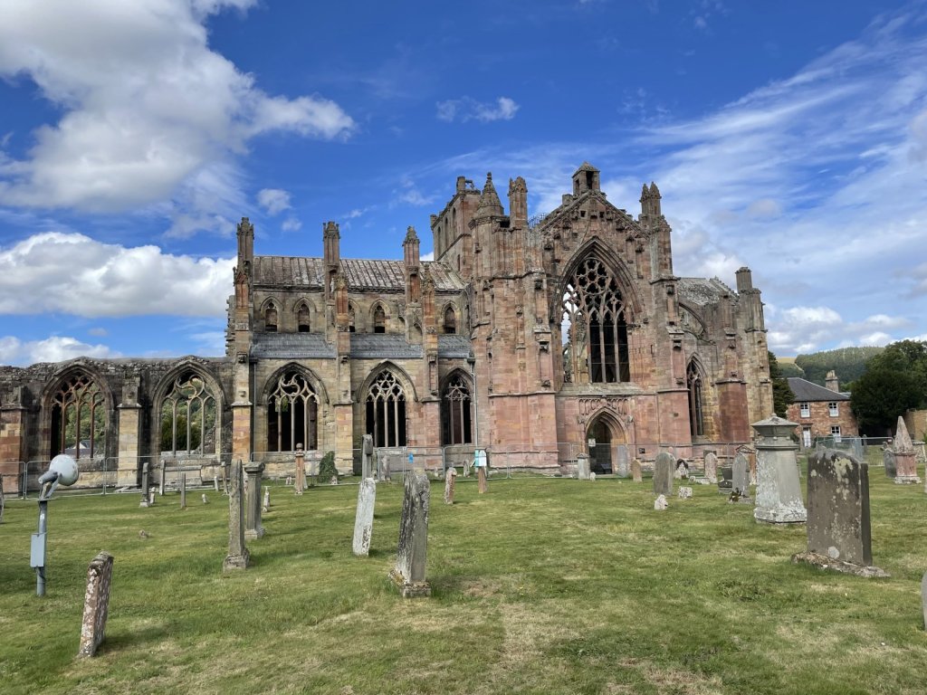 Ruine der Melrose Abbey mit Gräbern auf der Wiese davor