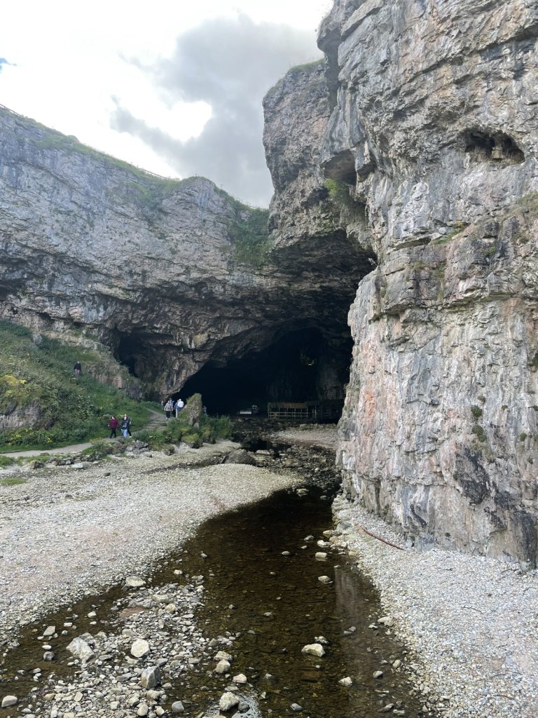 Eingang der Smoo Cave mit Bach in einer Felswand