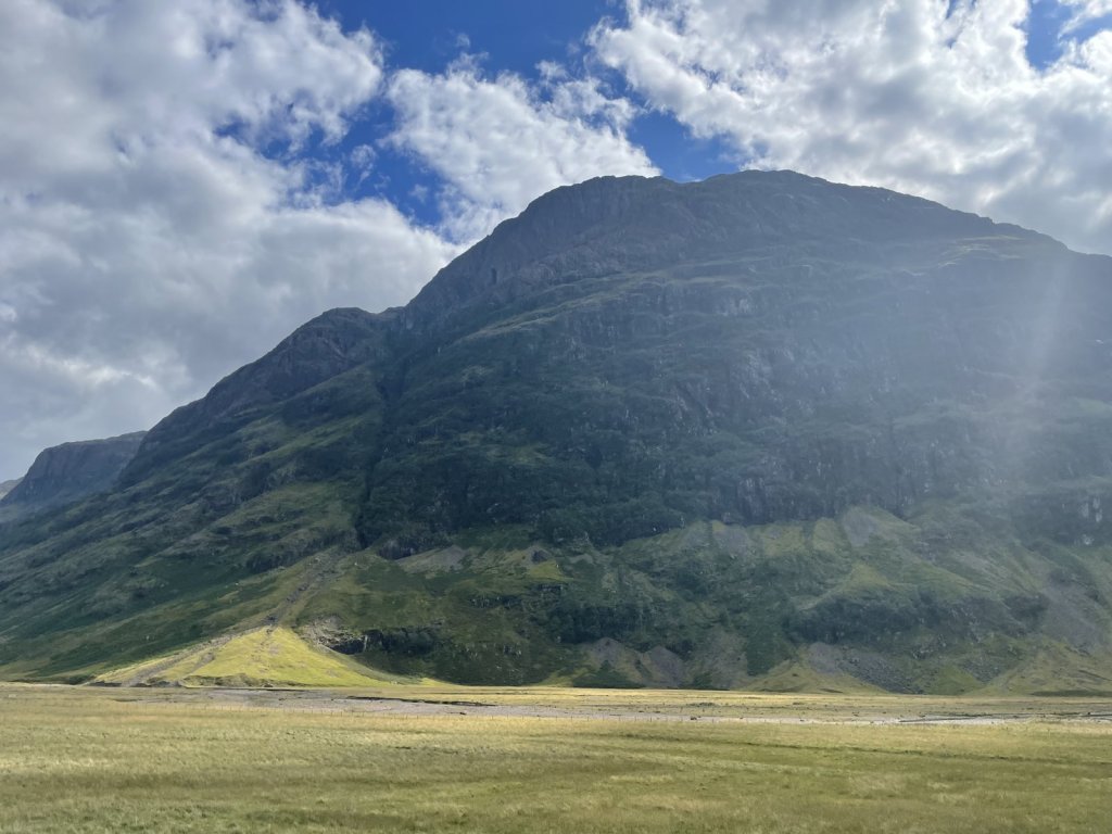 Steile grüne Bergflanke in Glen Coe unter Wolken