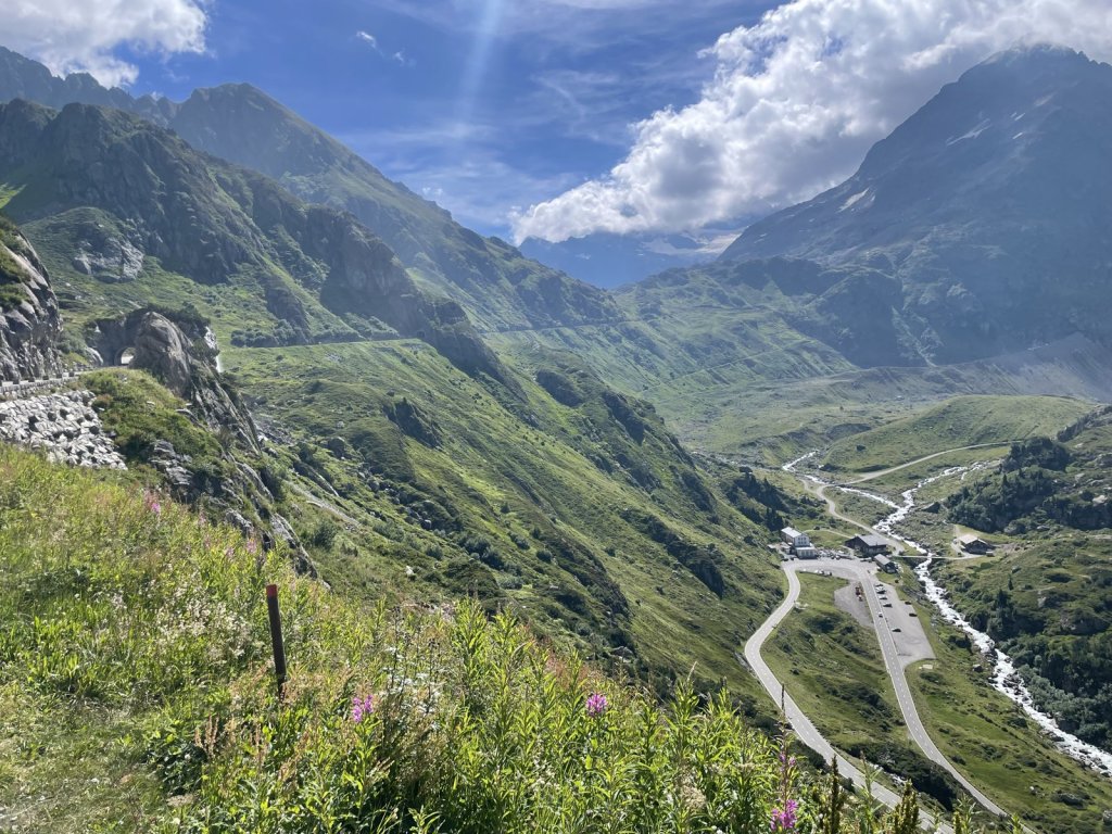 Straße windet sich in Serpentinen durch ein grünes Hochtal am Sustenpass