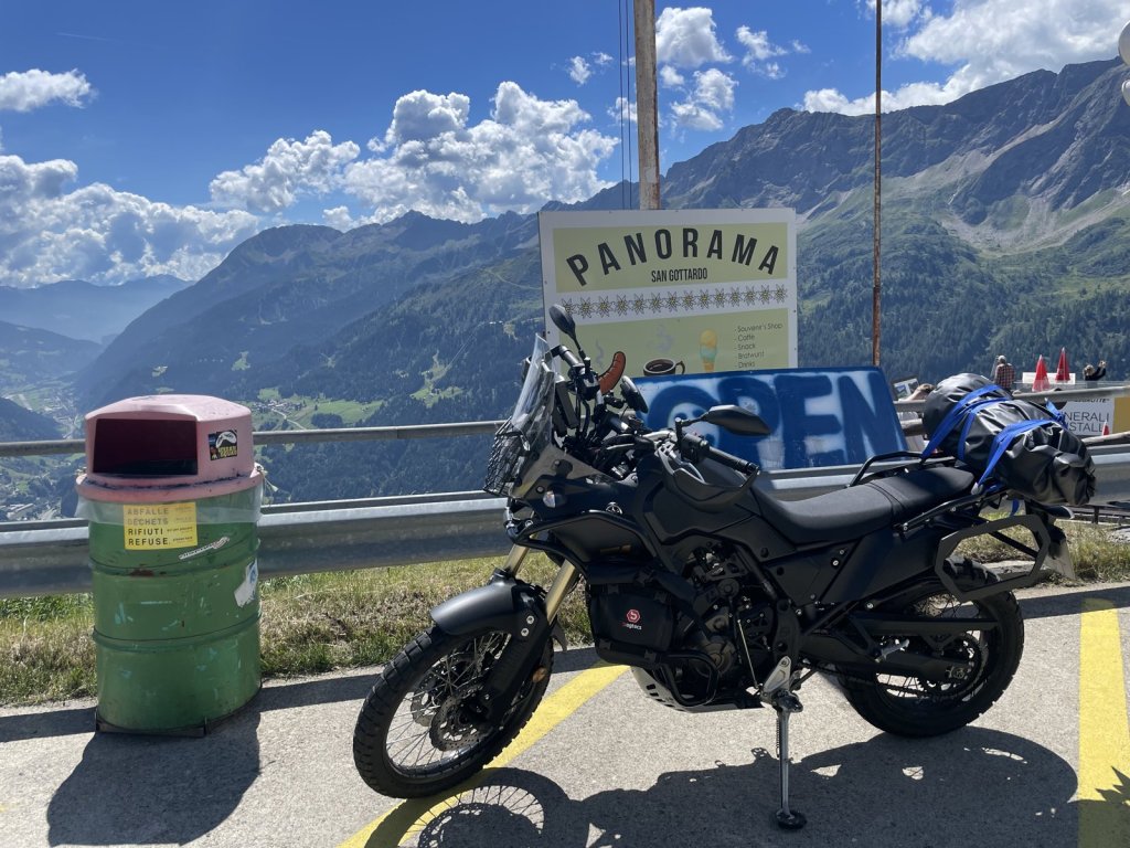 Motorrad an einer Aussichtsstelle mit Schild Panorama vor Bergen