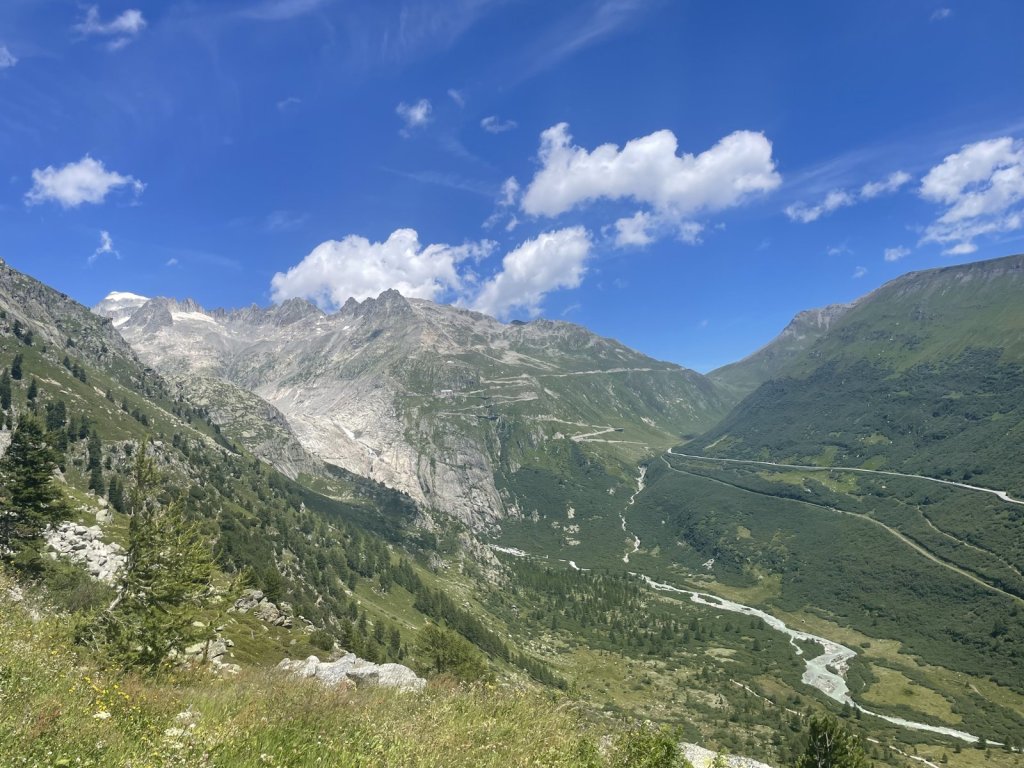 Passstraße in Serpentinen und eine Gletscherzunge in einem Hochgebirgstal