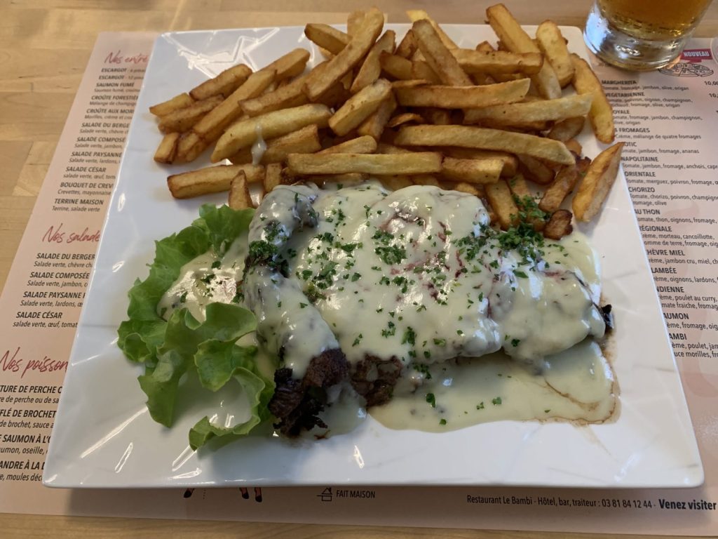 Teller mit Fleisch in Sahnesoße, Pommes und Salat