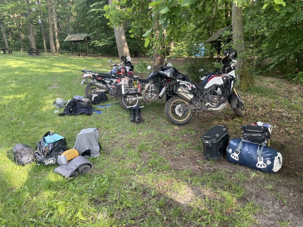 Motorräder und Gepäck auf einer Wiese im Wald bei Barlinek