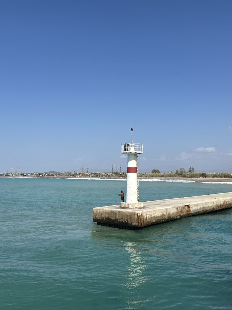 Weißer Leuchtturm an einer Mole am Meer